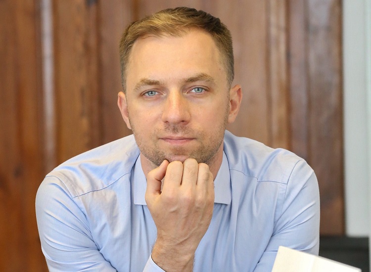 Młody mężczyzna w jasnoniebieskiej koszuli patrzy w obiektyw z brodą podpartą na dłoni. Ma krótkie ciemnoblond włosy, niebieskie oczy i lekki zarost.Humala Alexander, fot. Anatoly Kleshchuk